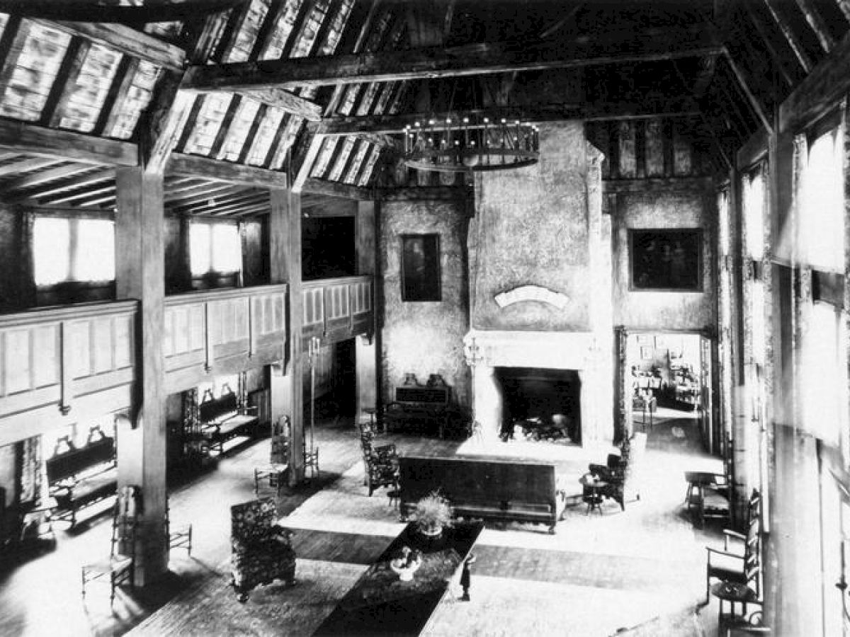 Vintage photo of Lake Arrowhead's Great Hall with a fireplace, timber beams, and sofas.