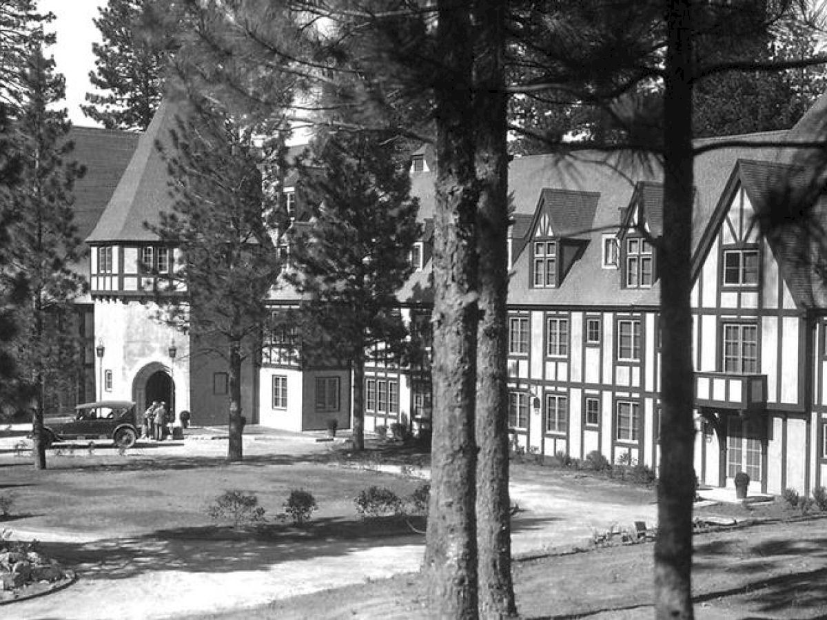 Vintage image of Lake Arrowhead's Tudor-style buildings with archway, surrounded by pine trees