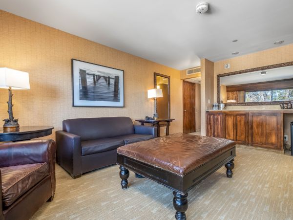 A hotel-style lounge with sofas and lamps, a large framed wall photo, and a wooden bar counter with mirrors.