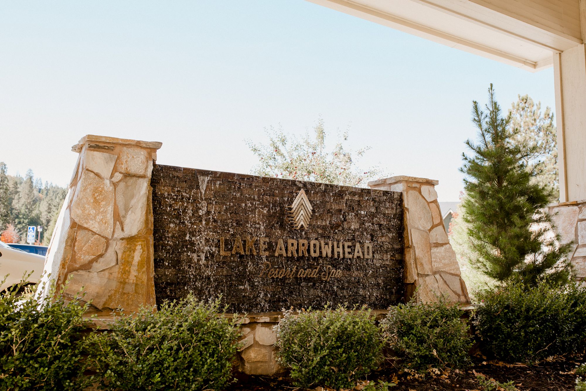 A stone sign at a gated entrance reads &ldquo;Arrowhead&rdquo; with landscaping and trees around, under a covered entry&mdash;looks like a community sign.