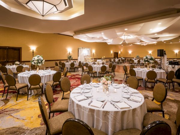 Elegant banquet hall with set tables, floral centerpieces and sophisticated decor.
