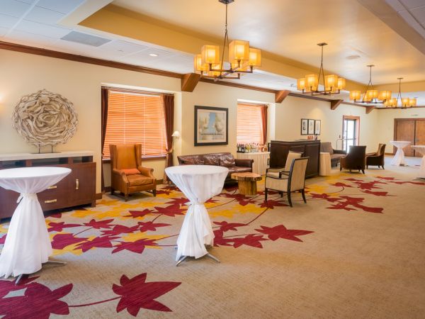 Elegant room with modern decor, high ceilings, chandeliers, and round tables.