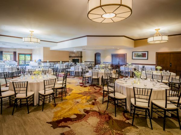 Elegant dining hall set up with round tables, white tablecloths, and fancy settings.