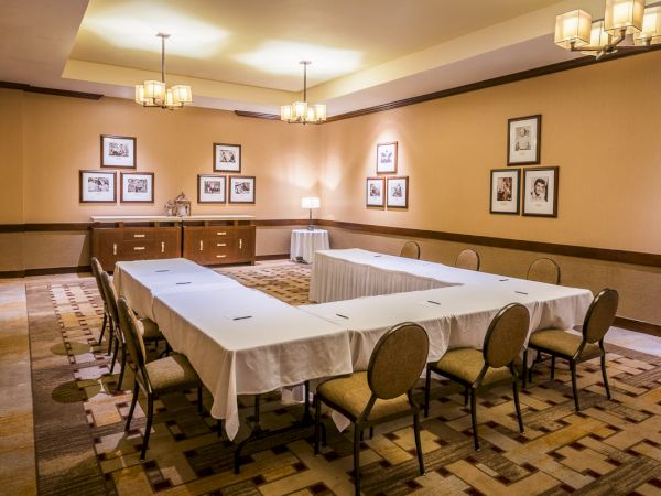 Conference room with a long table, chairs, framed pictures on walls, and overhead lighting.