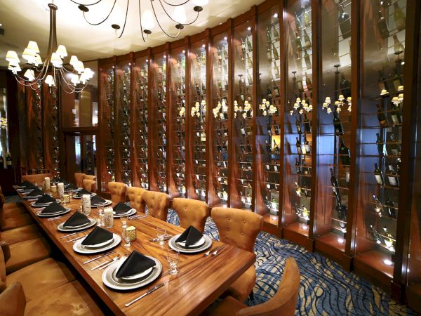 Elegant dining room with a long table, plush chairs, and decorative wine racks.