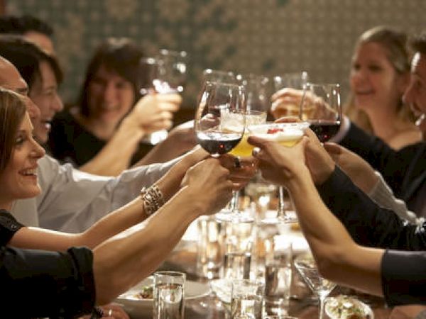 Group of people toasting with wine glasses at a dinner table, celebrating.