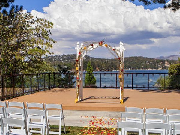 Outdoor wedding setup with chairs, a decorated arch, and a lake view.