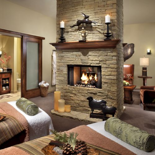Cozy living room with a stone fireplace, lit candles, holiday decor, and plush seating.