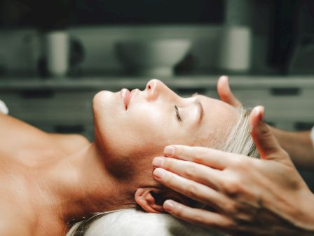 Close-up of a man receiving a relaxing facial massage, with hands gently working on his cheek and jaw.