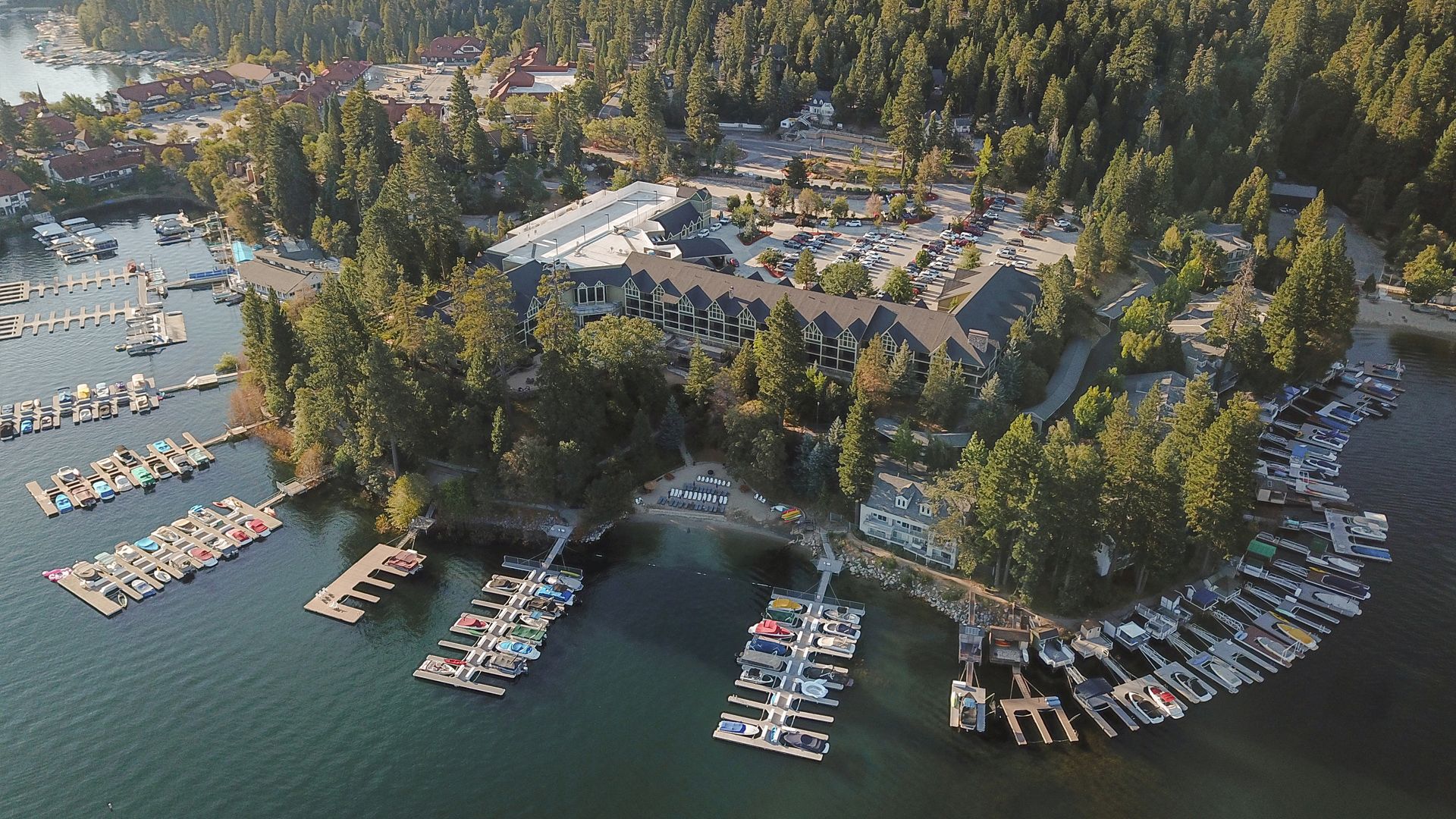 An ariel view of the resort showing the property surrounded by trees next to a lake filled with boating docks.