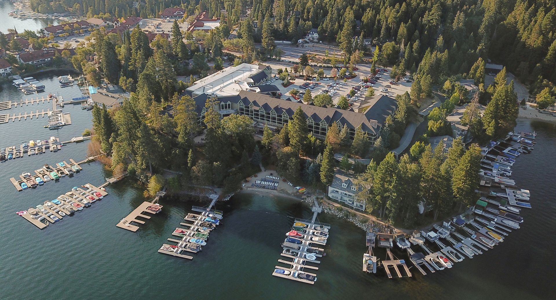An ariel view of the resort showing the property surrounded by trees next to a lake filled with boating docks.
