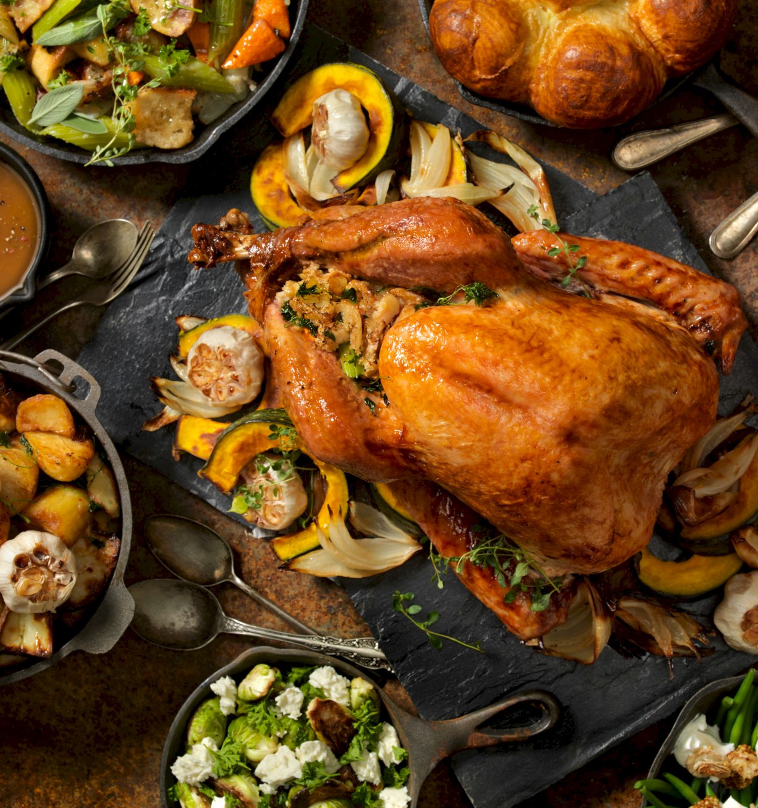 Roasted whole chicken with vegetables, gravy, and fresh herbs on a rustic serving tray.