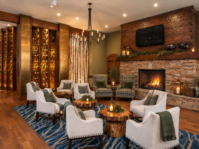 Cozy lodge living room with plaid armchairs, a stone fireplace with candles, a flat-screen TV, and warm wood-and-brick d&eacute;cor.