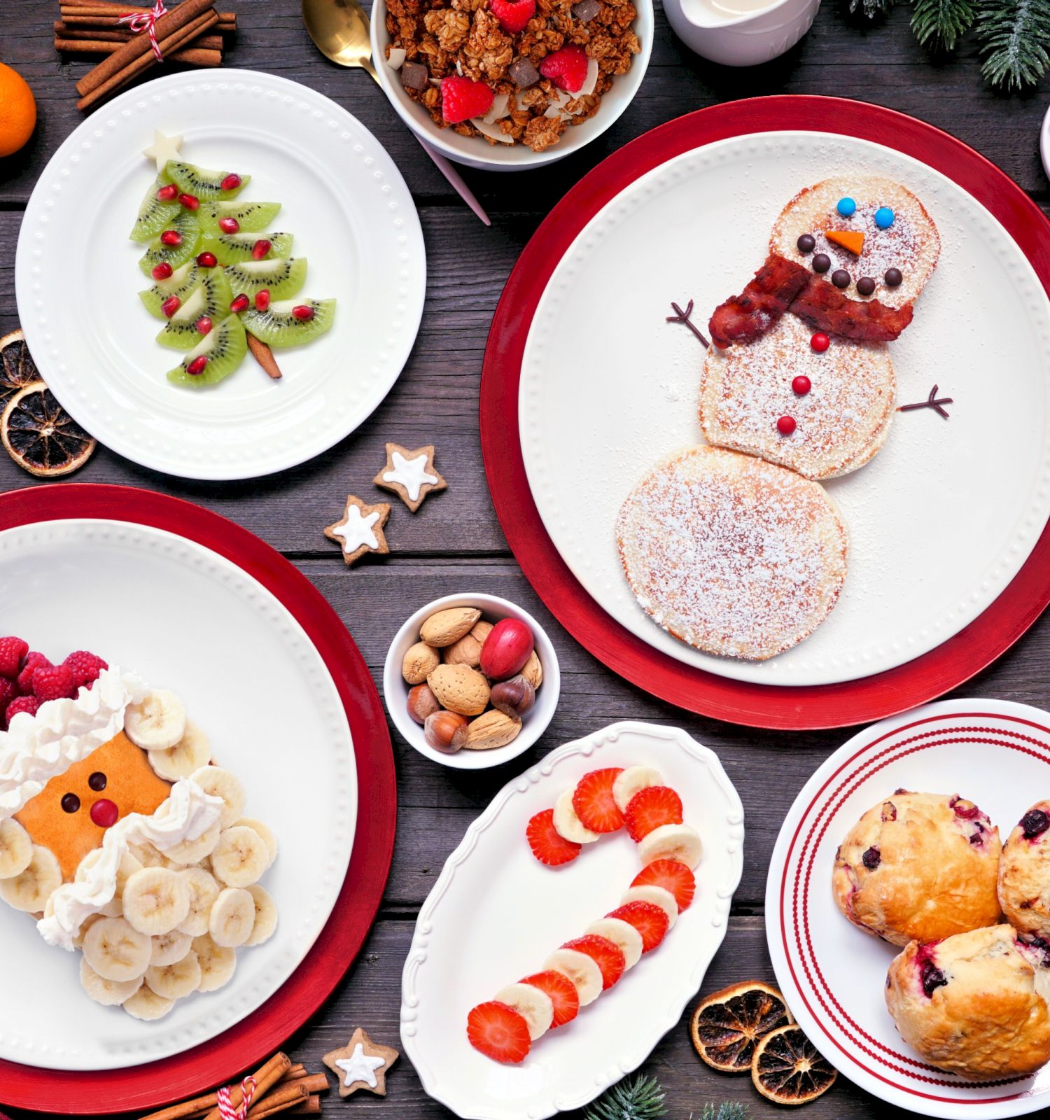 A Christmas-themed spread of plate desserts: snowman pancakes, fruit-topped snacks, cookies, and warm hot chocolate for cozy holiday treats.