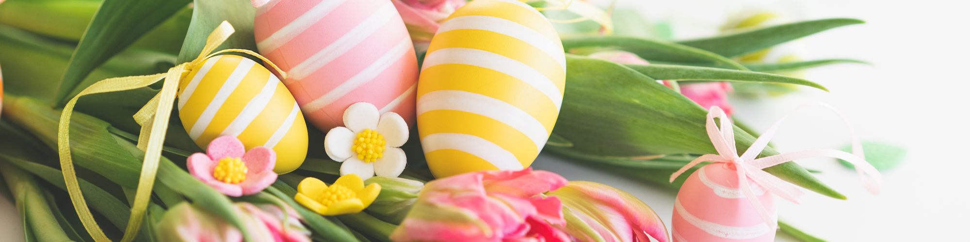 A bouquet of pink tulips with striped pastel Easter eggs and small decorative flowers on a white background.
