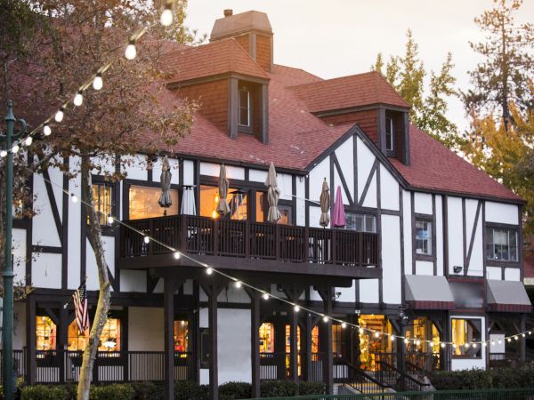 A Tudor-style building with a red roof and string lights in the evening setting.