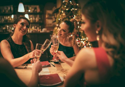 A group of friends toasting champagne glasses at a warmly lit festive dinner.