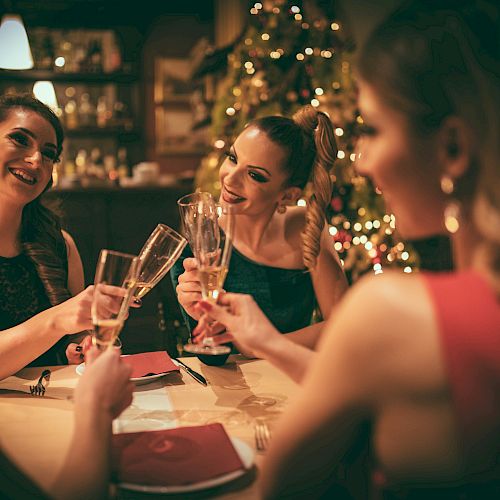 A group of friends toasting champagne glasses at a warmly lit festive dinner.