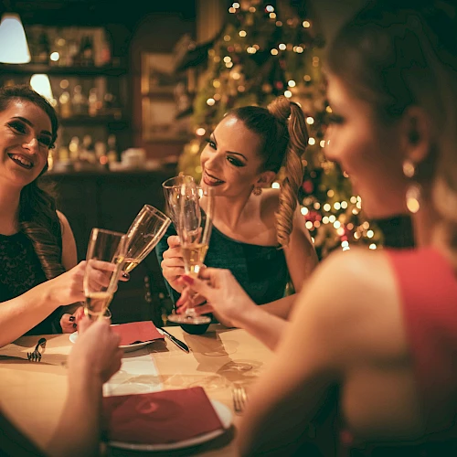 A group of friends toasting champagne glasses at a warmly lit festive dinner.