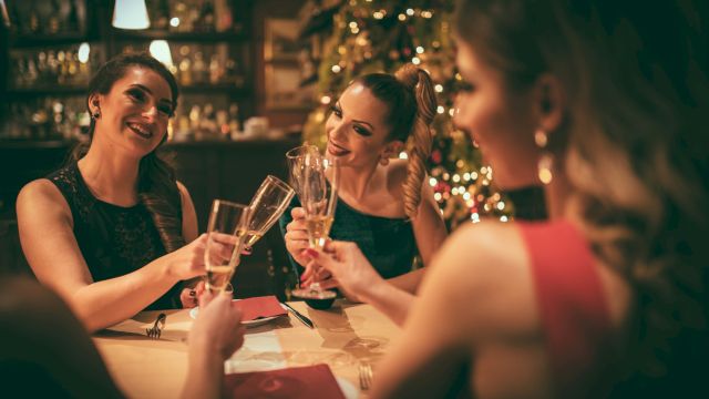 A group of friends toasting champagne glasses at a warmly lit festive dinner.