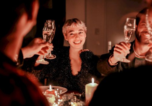 A group of people at a candlelit dinner, raising champagne flutes in a toast, smiling and enjoying the celebration.