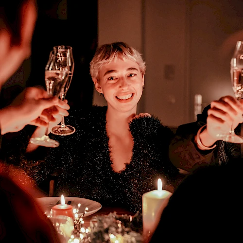 A group of people at a candlelit dinner, raising champagne flutes in a toast, smiling and enjoying the celebration.