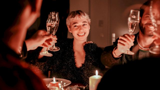 A group of people at a candlelit dinner, raising champagne flutes in a toast, smiling and enjoying the celebration.