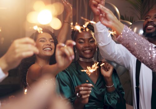 A group of friends at a celebration, holding sparklers and smiling as they toast and enjoy a festive night together.