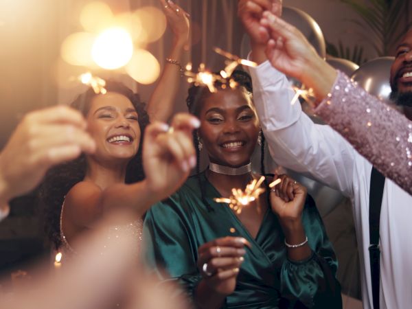 A joyful group at a party, holding sparklers and toasting, smiling and celebrating together.