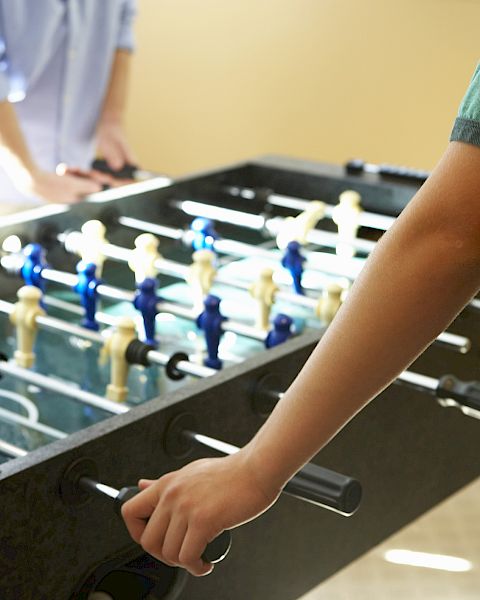 A person playing on a foosball (table soccer) table, moving the rods with their hands to control the players.